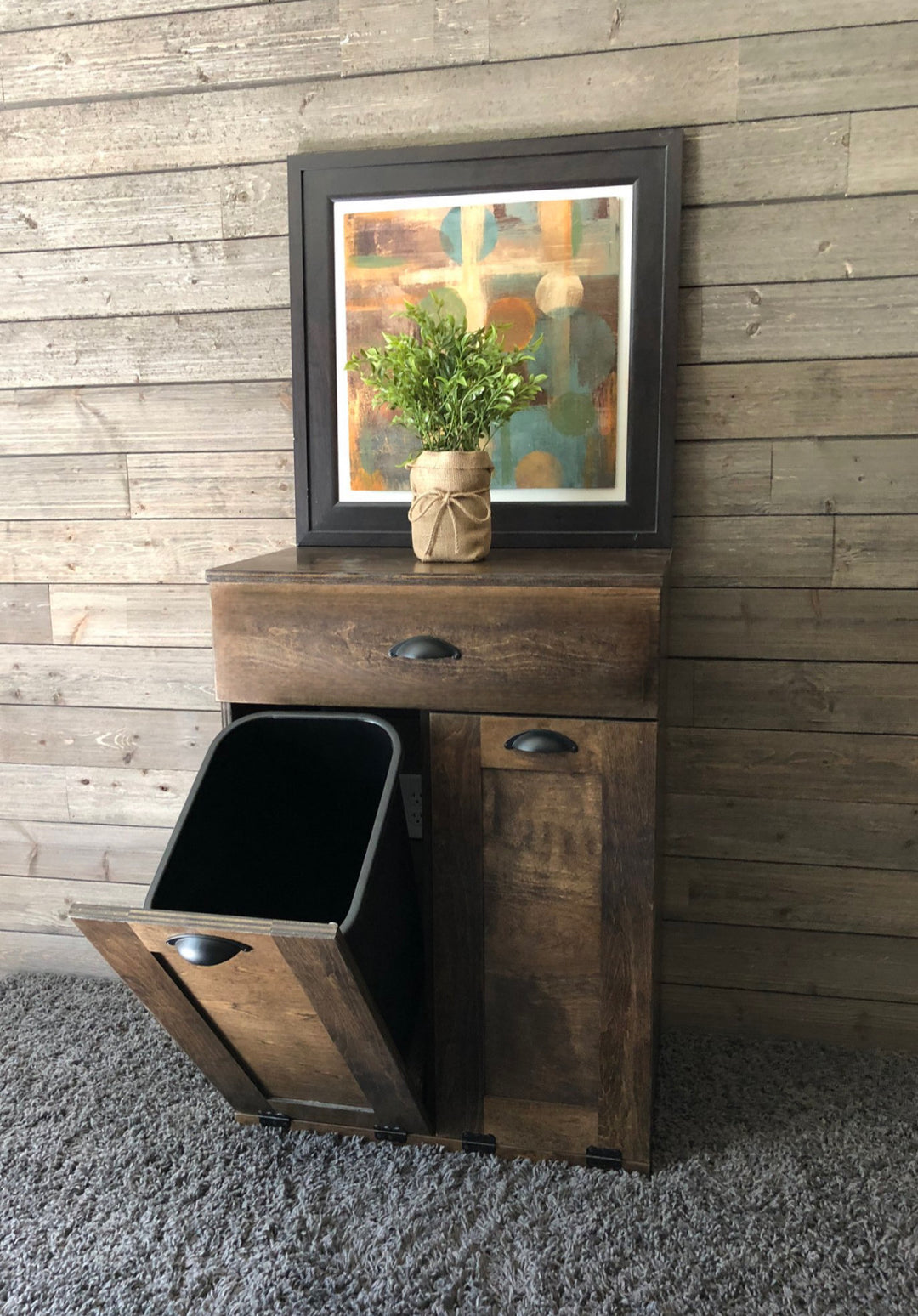 Counter high, slim trash cabinet design. Includes a storage drawer in dark brown