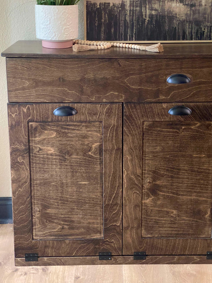 Furniture style triple tilt out trash cabinet in dark brown with a storage drawer