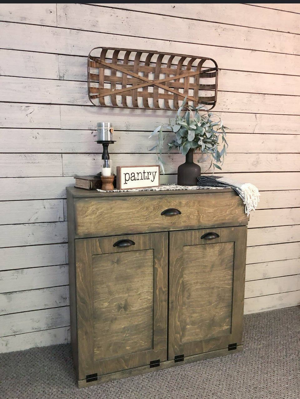 Counter tall hidden trash cabinet with a storage drawer in aged barrel stain