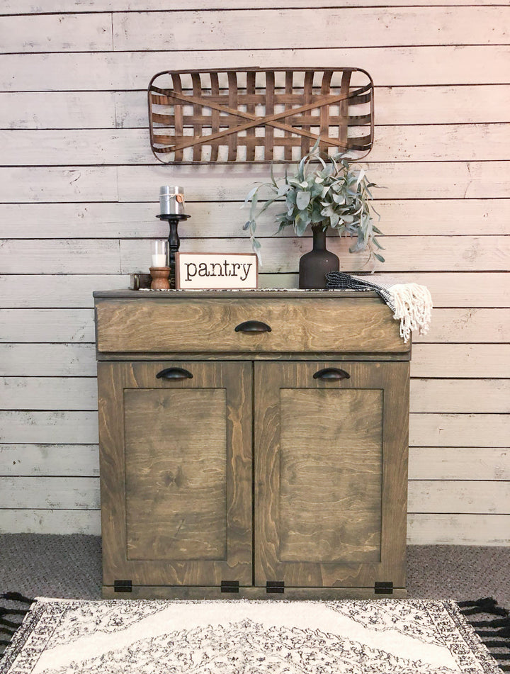 Counter tall hidden trash cabinet with a storage drawer in aged barrel stain