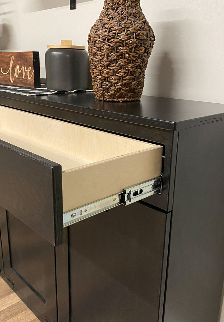 Free standing hidden trash cabinet with a storage drawer in black stain