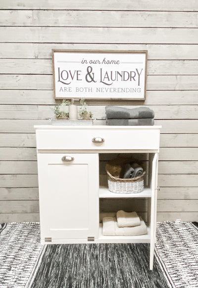 White double size tilt out laundry hamper with a cabinet and drawer.  Handle options are gold, silver, or black. Panel options are cedar look panel, chalkboard, barn metal, or flat front.