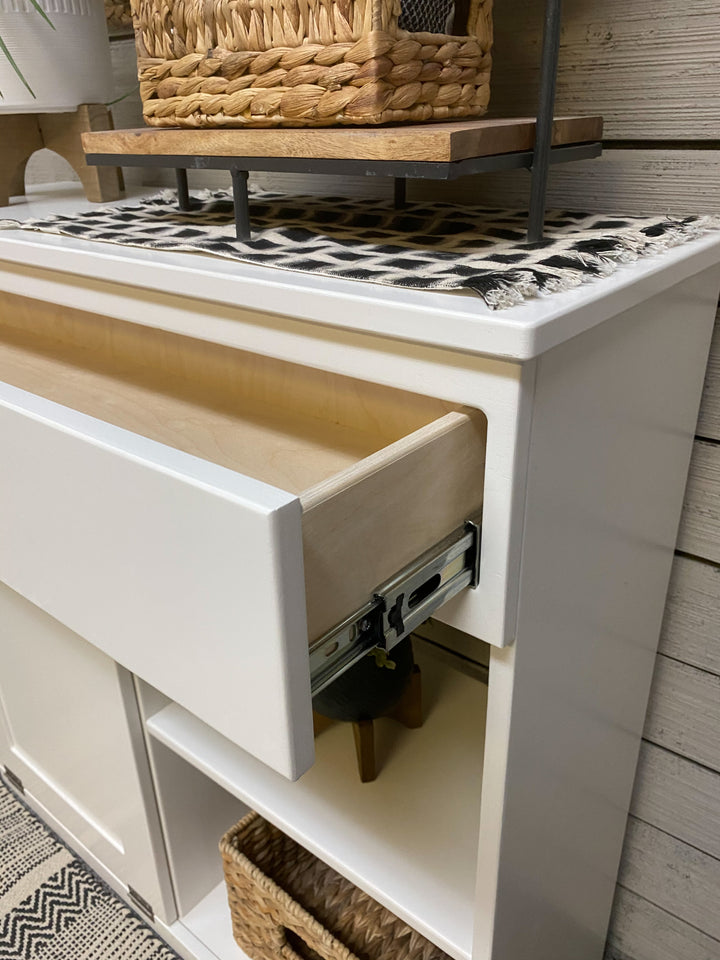 Double size- trash compartment with a storage drawer and open shelving in white